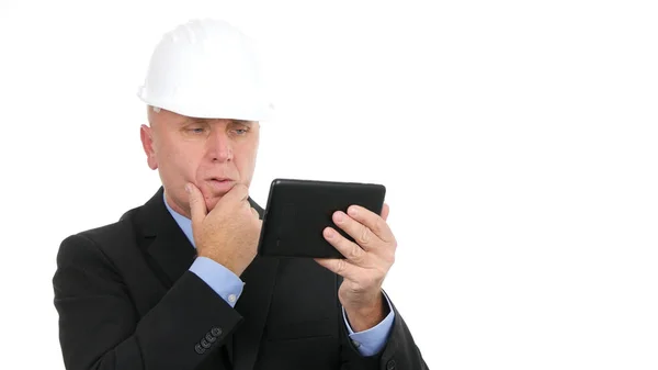 Afbeelding met bezorgde zakenman die hard Hat draagt en elektronische tablet gebruikt — Stockfoto