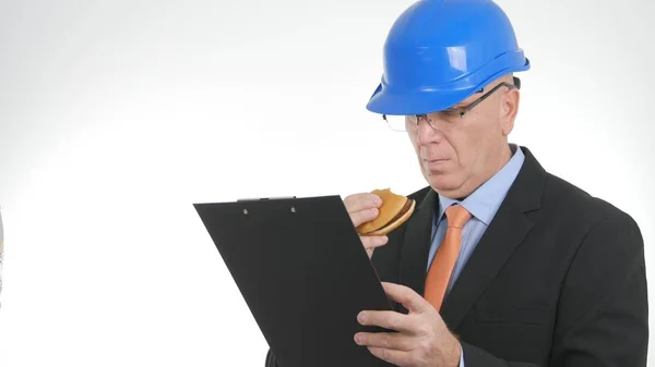 Engenheiro faminto ler da agenda e comer um sanduíche saboroso — Fotografia de Stock