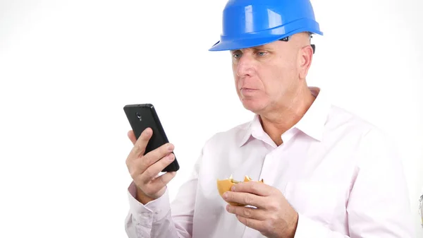 エンジニアは、スマートフォンの通信を使用しておいしいサンドイッチとテキストを食べる — ストック写真