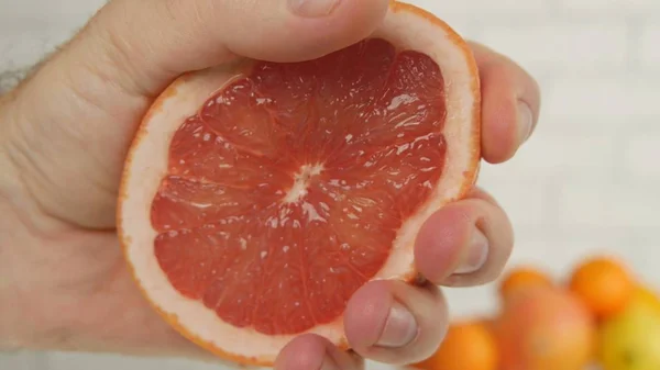 Imagen de pomelo con la mano presionando la mitad de la fruta y exprimir el jugo — Foto de Stock