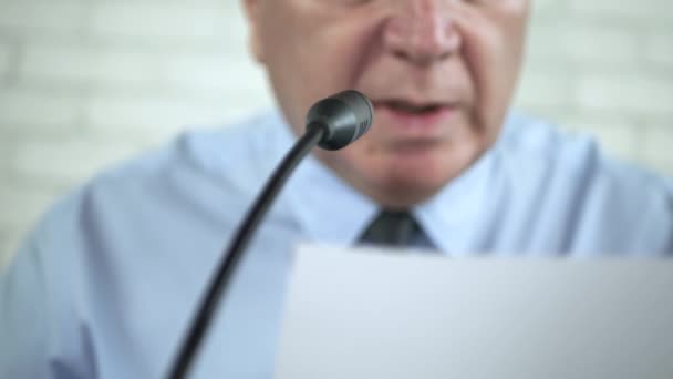 Geschäftsmann liest ein Dokument und spricht am Mikrofon in einer Konferenz — Stockvideo