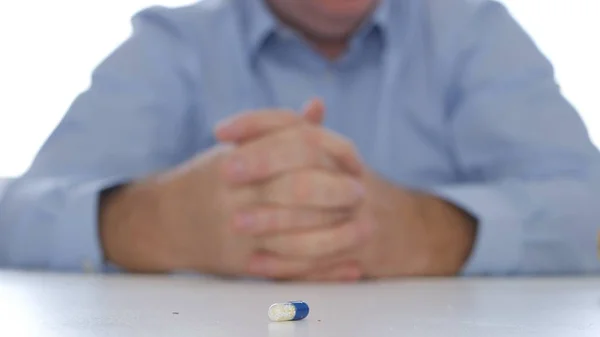 Imagen con un paciente que sufre mirando a una píldora médica desde la mesa — Foto de Stock