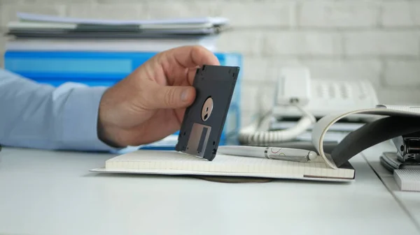 Imagen con un hombre de negocios en la oficina con un disquete en la mano — Foto de Stock