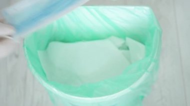 Doktor, hastane vardiyası bittikten sonra yavaş çekimde tek kullanımlık eldiven ve maskeli çöp kutusuna attı.