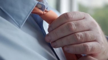 Resmi, mavi gömlek giyen ve turuncu kravata düğüm atan şık bir iş adamıyla kapatın.