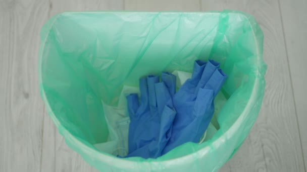 El médico tira a la basura guantes desechables y mascarilla usada después del cambio de servicio del hospital, equipo médico en la caja de basura — Vídeo de stock