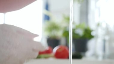 Mutfakta Eldiven takmış bir adam temiz suyla maydanozu yıkıyor.