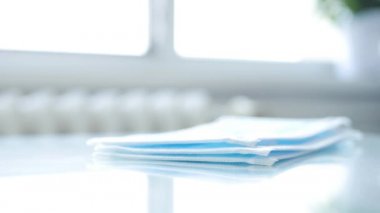 Doktor, hastane odasında bir paket cerrahi maskeyi tek tek sayıyor ve kontrol ediyor.