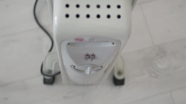 Człowiek ustawia temperaturę grzewczą grzejnika elektrycznego w domu, aby utrzymać robaka w chłodni — Wideo stockowe