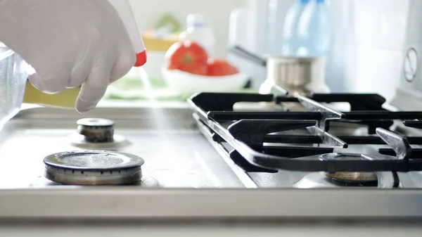 Persona ocupada en la cocina que usa guantes limpia con solución la estufa de cocina . — Foto de Stock