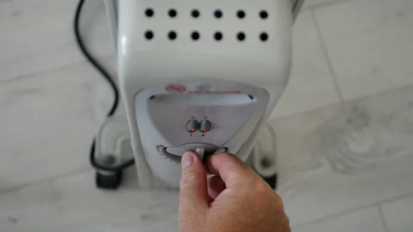 Homem define a temperatura de aquecimento de um radiador elétrico em casa em uma sala fria — Fotografia de Stock