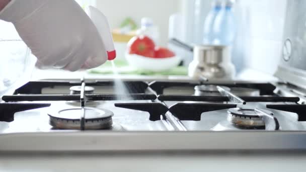 Movimento lento com uma governanta vestindo luvas de proteção limpa com solução de pulverização o fogão na cozinha — Vídeo de Stock