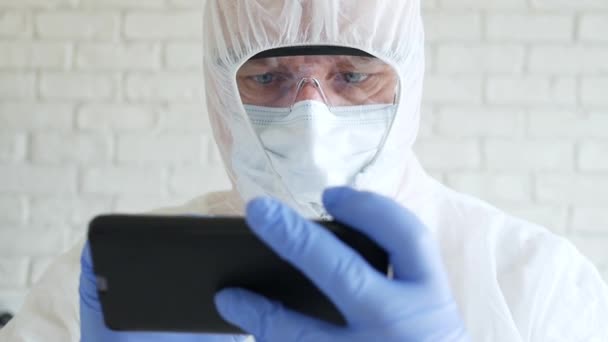 医院隔离时穿着防护服、手套、面罩和眼镜的医生使用手机 — 图库视频影像