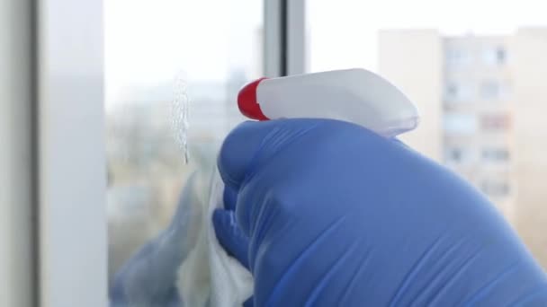 Close Up Man Hands with Blue Gloves Καθαρισμός παραθύρου με τη χρήση ψεκασμένου υγρού απολύμανσης κατά της μόλυνσης από COVID-19 — Αρχείο Βίντεο