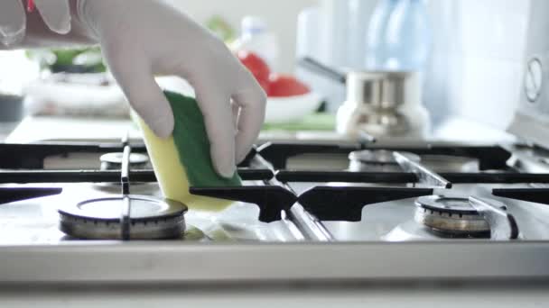 Une femme de ménage portant des gants de protection nettoie avec une solution de pulvérisation la cuisinière dans la cuisine — Video