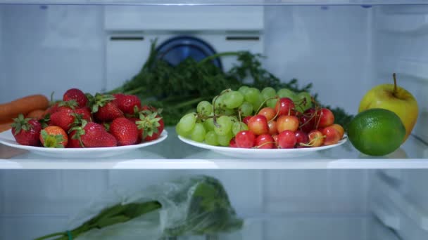 Tiro com morangos frescos e frios, cerejas e uvas em uma geladeira de cozinha — Vídeo de Stock