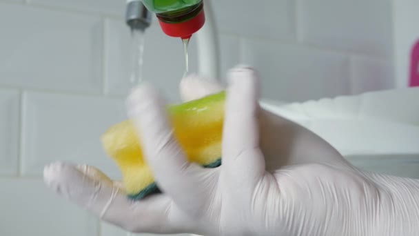 Mężczyzna w kuchni zmywa naczynia z gąbką i płynem do zmywania naczyń — Wideo stockowe