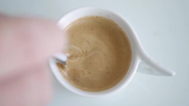 Une personne se mélange avec une cuillère à café une tasse de café aromatisé avec du lait frais — Video