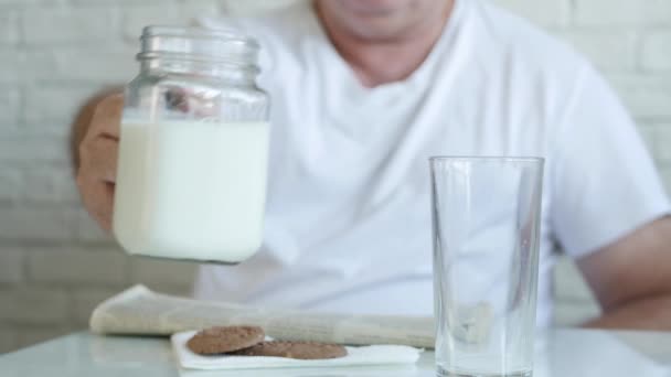 Jedna osoba Přečtěte si noviny a naplňte sklenici čerstvým mlékem na snídani, těší chutné a plné vitamínů mléka — Stock video