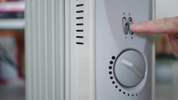 Человек устанавливает температуру нагрева электрического радиатора дома — стоковое видео