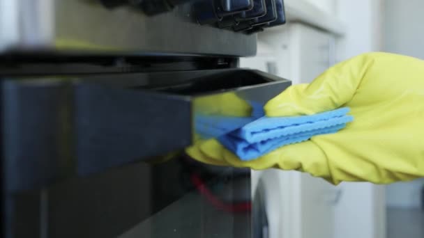 Las manos del hombre de primer plano que usan guantes blancos de protección para el hogar limpian la puerta de la estufa de la cocina y sus accesorios — Vídeos de Stock