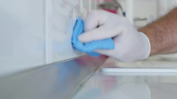 Man met witte beschermende handschoenen in handen, reinigt en desinfecteert keuken Faience en meubilair — Stockvideo