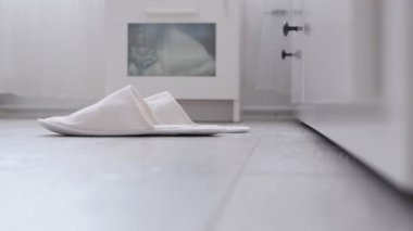 Yatak odasında terlik giyen yaşlı bir insanın ayakları.