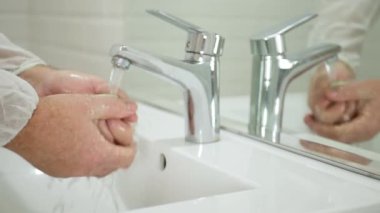 Tuvaletteki adam sabun ve suyla ellerini virüslerden temizliyor ve dezenfekte ediyor.