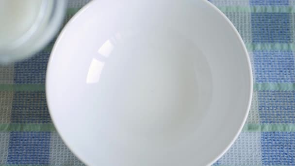 De cerca con una persona en el desayuno que llenan de leche fresca un tazón de la mesa — Vídeos de Stock