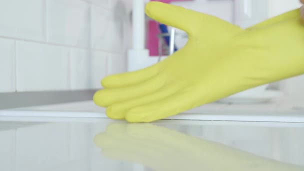 Homem coloca suas luvas de proteção amarelas em suas mãos se preparando para começar a limpar na cozinha — Vídeo de Stock