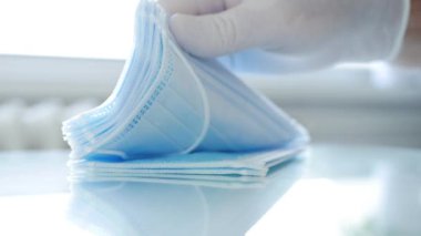 Doktor, hastane odasında cerrahi maske paketini tek tek sayıyor ve kontrol ediyor.