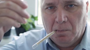 Coronavirus semptomları gösteren bir adam bir hastanede vücut ısısını ölçmek için civa ölçeğinde termometre kullanıyor.