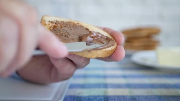 Hladová osoba Rozprostřít plátek toastu s čokoládovou smetanou v dopoledních hodinách na snídani — Stock video