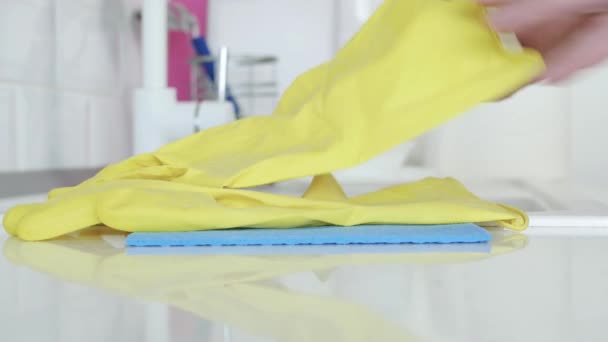 Мужчина берет жёлтые домашние перчатки и влажные салфетки на раковину, готовясь начать уборку на кухне — стоковое видео