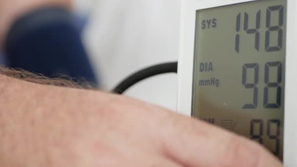 Doktor, dijital ekranlı modern bir elektronik cihaz kullanarak hastanın kan basıncını ölçüyor. — Stok video