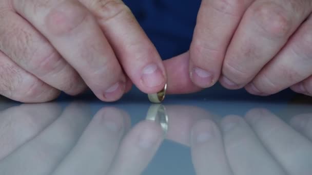 Ein gelangweilter Mann spielt mit seinem Ehering auf dem Tisch, einem Symbol der Ehe — Stockvideo