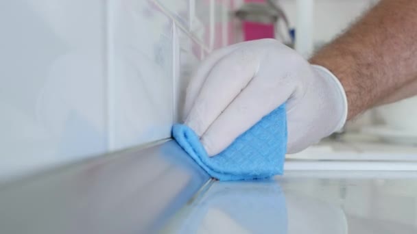 Mężczyzna z białymi rękawiczkami ochronnymi w rękach, czyści i dezynfekuje kuchnię Fajans i meble — Wideo stockowe