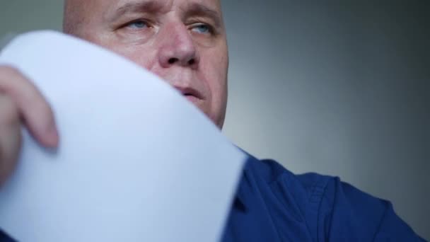 Un hombre en una habitación donde hay mucho viento caliente usando una hoja de papel y limpia el sudor de su frente — Vídeos de Stock