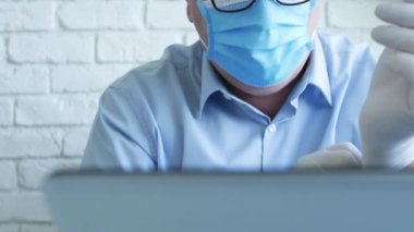 Maske ve Koruyucu Eldiven Giyen Doktor Laptop İletişim kullanıyor