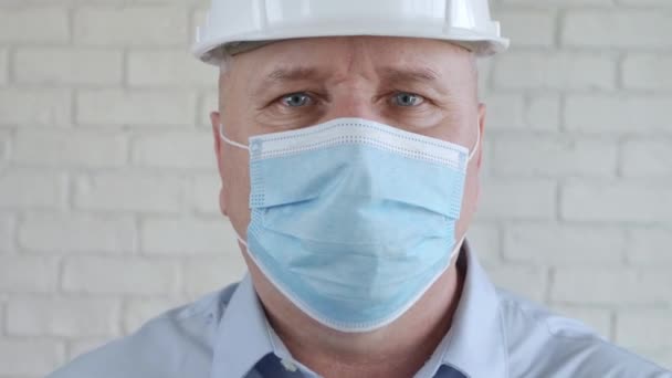 Портрет з інженером в захисній медичній масці для обличчя та шоломі безпеки — стокове відео