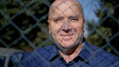 Metalik Çitin Arkasında Gülümseyen Mutlu Yaşlı Bir Kişi Görüntü