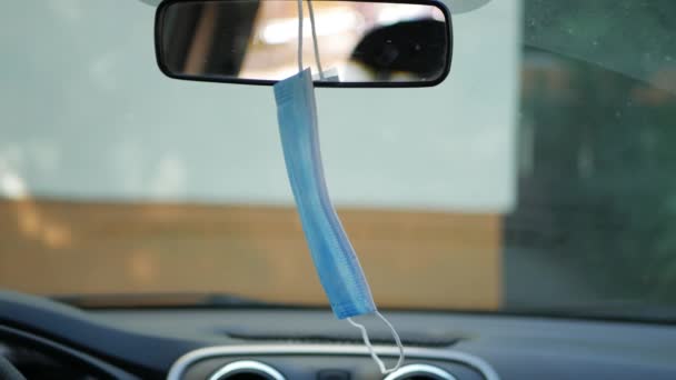 Máscara facial médica usada pelo motorista pendurado no espelho retrovisor no carro, proteção contra o coronavírus — Vídeo de Stock