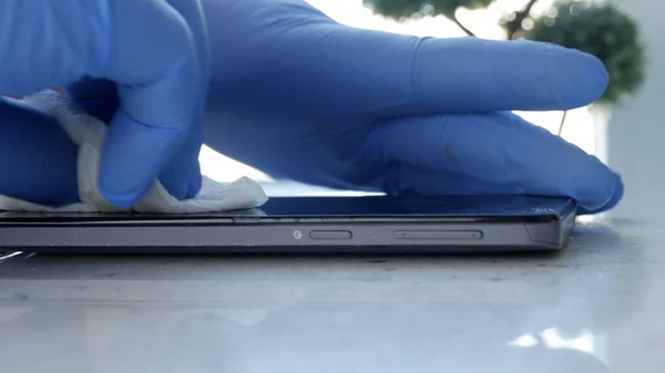 Bild mit Doktorhänden, die Schutzhandschuhe tragen und ein Smartphone mit Desinfektionslösung reinigen — Stockbild Bild Mit Doktorhänden Die Schutzhandschuhe Tragen Und Ein Smartphone Mit — Stockfoto
