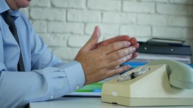 Ofis odasında eski bir iletişim teknolojisini kullanarak ayakta duran ve telefonla konuşan bir iş adamı resmi