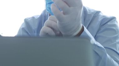 Maske ve Koruyucu Eldiven Giyen Doktor Laptop İletişim kullanıyor
