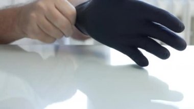Doktor ellerine siyah koruyucu tıbbi eldiven takıyor.