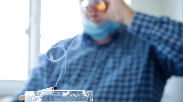 얼굴에 마스크를 마시고 담배를 피우는 남자의 — 스톡 사진