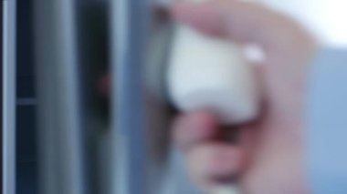 Aç adam buzdolabının kapısını açar ve içine yoğurt koyar.