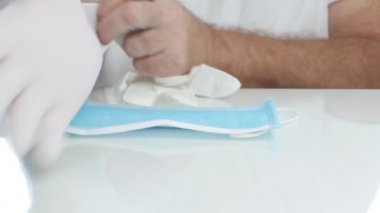 Hastanedeki doktor ellerine beyaz koruyucu eldiven takıyor.