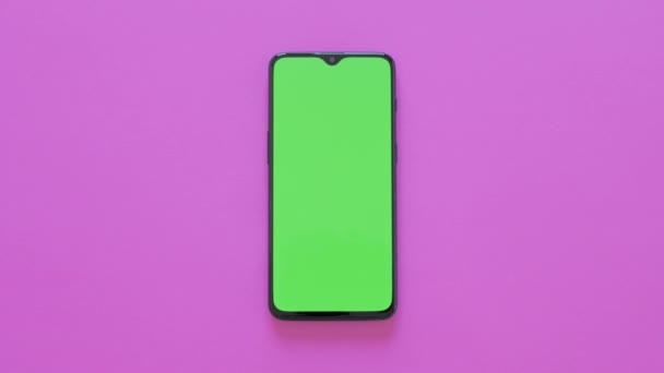 Groen scherm-een moderne smartphone ligt op een roze achtergrond — Stockvideo